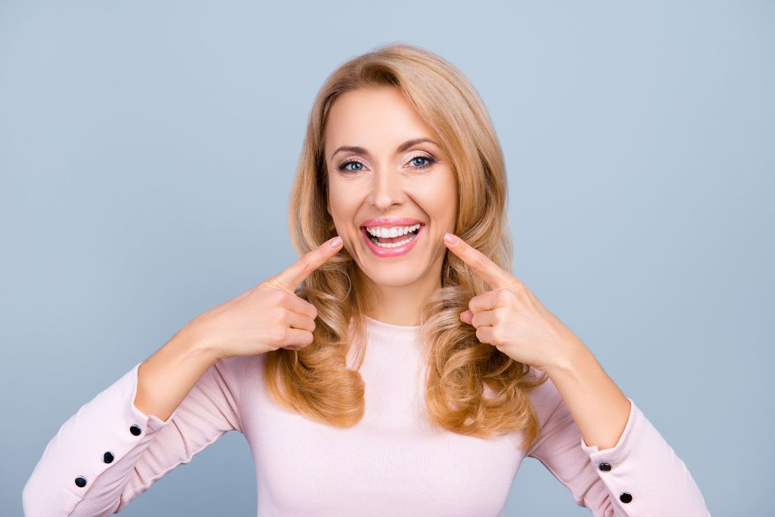 mujer sonriendo señalándose la boca