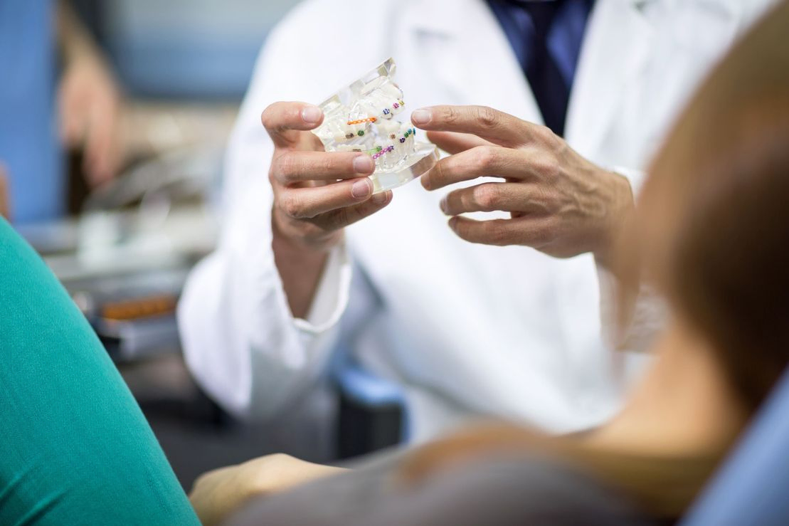 dentista mostrando molde de dientes a paciente